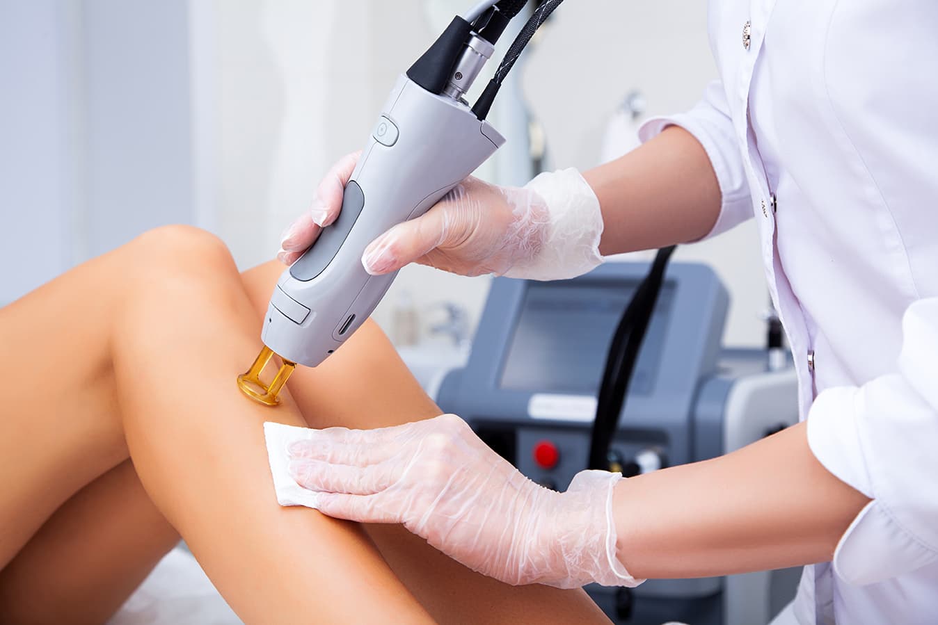 Laser hair removal on the leg A specialist performing a laser procedure on a leg, an alexandrite laser used for hair and tattoo removal.